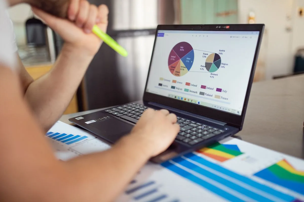 Gestor de vendas analisando relatórios e gráficos de desempenho da equipe em laptop
