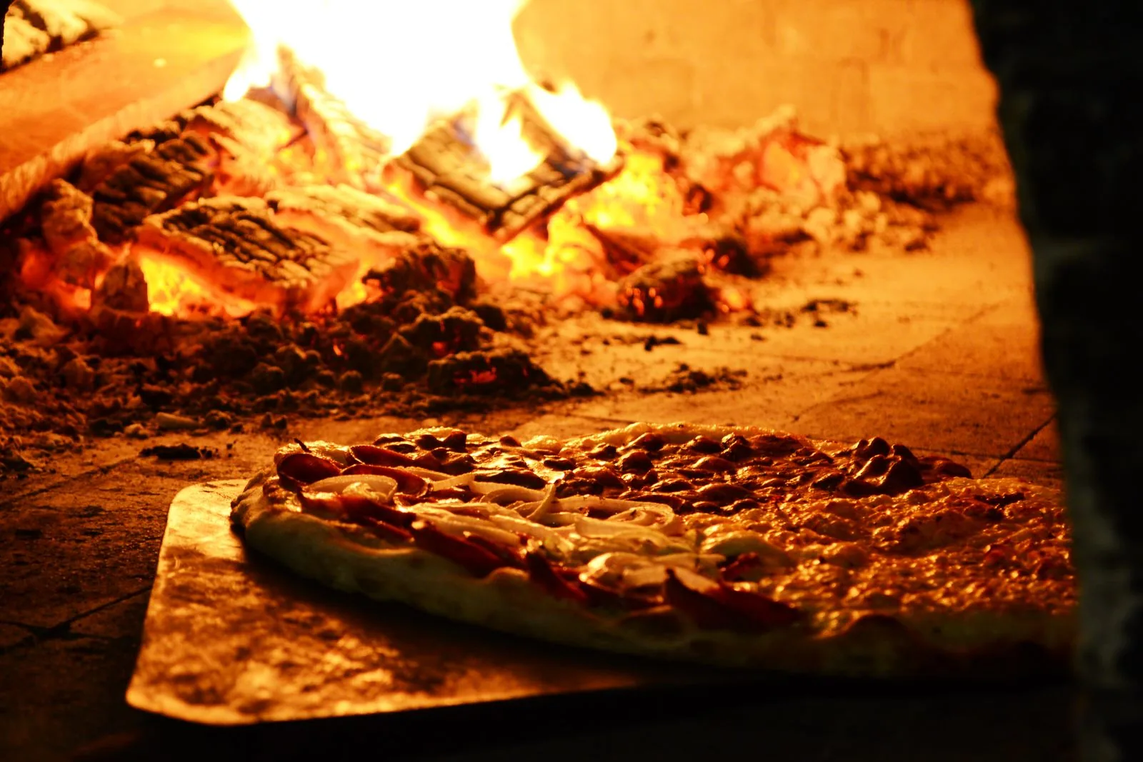 Pizza assando no forno a lenha de uma pizzaria — sistema para pizzaria